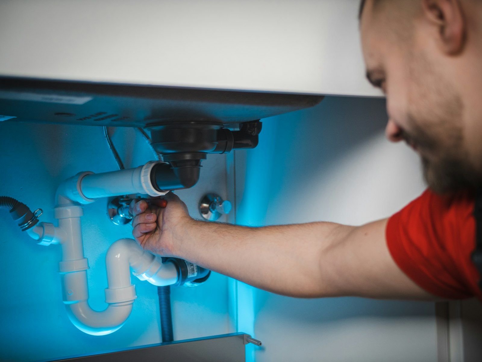 Plumber working on exposed wall pipes during an emergency repair